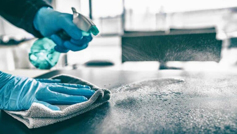 Cleaning home table sanitizing kitchen table surface with disinfectant spray bottle washing surfaces with towel and gloves. COVID 19 prevention sanitizing inside.